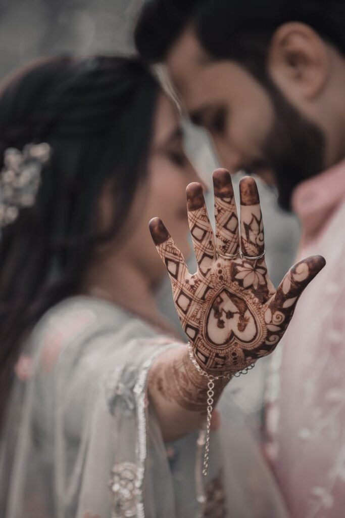 pexels-photo-12165511-12165511 Close-up of a bride showing mehndi on her hand while embracing her groom, symbolizing love and tradition.